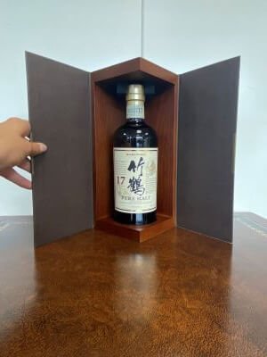 Foto van whiskyfles met hand van persoon in beeld